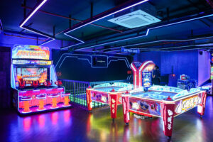 Indoor arcade games and air hockey area at Rumble Zone Gurgaon featuring neon-lit gaming machines and interactive play zones.