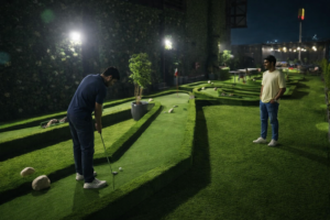 Mini golf in Gurgaon at Rumble Zone with two young adults playing on a modern green turf course at night
