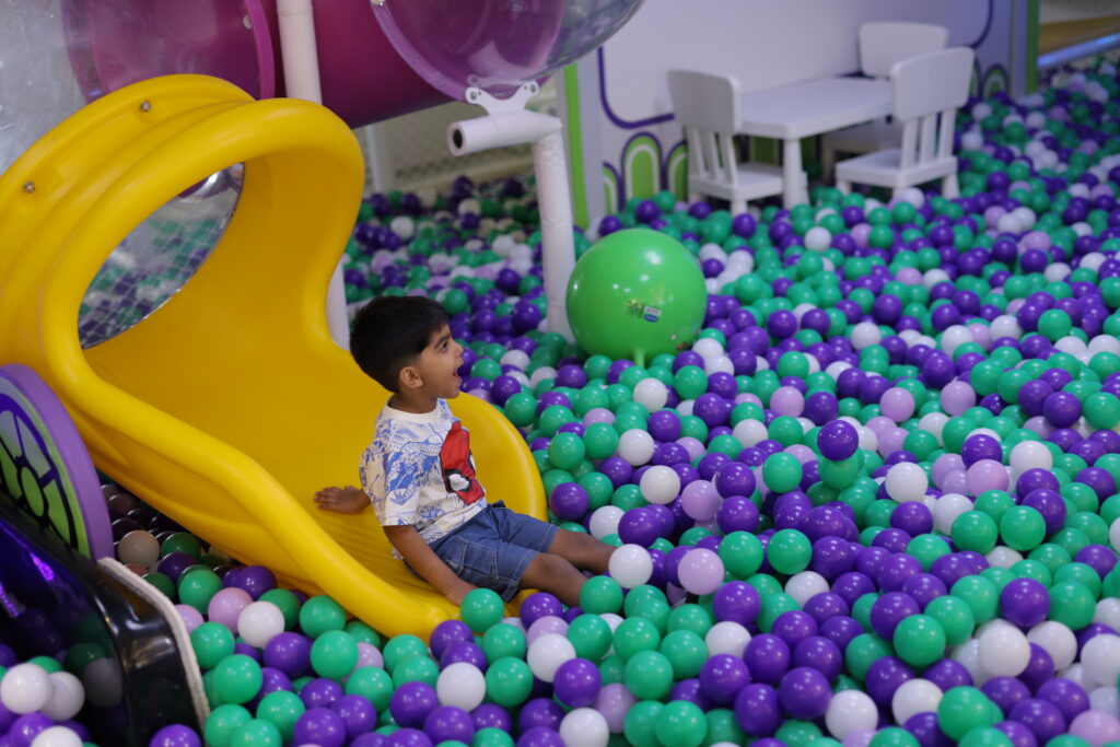 kids play area in gurgaon with a child enjoying a ball pit and slide at an indoor gaming zone