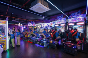 Students enjoying arcade games at a school trip venue in Gurgaon, with racing simulators, neon lights, and indoor gaming activities.